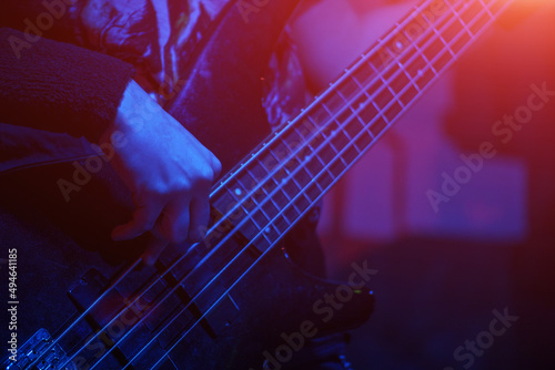 The bass guitarist plays the bass guitar in the spotlight. Selective focus