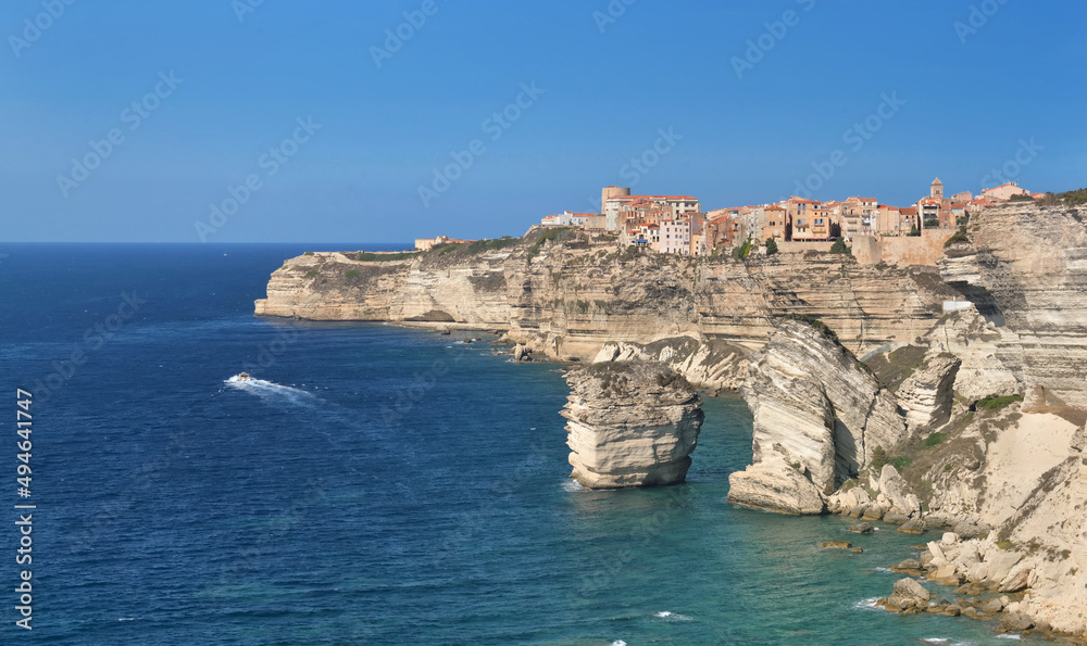 Bonifacio citadel  above  limestone cliff overlooking the sea on clear blue sky- corsica