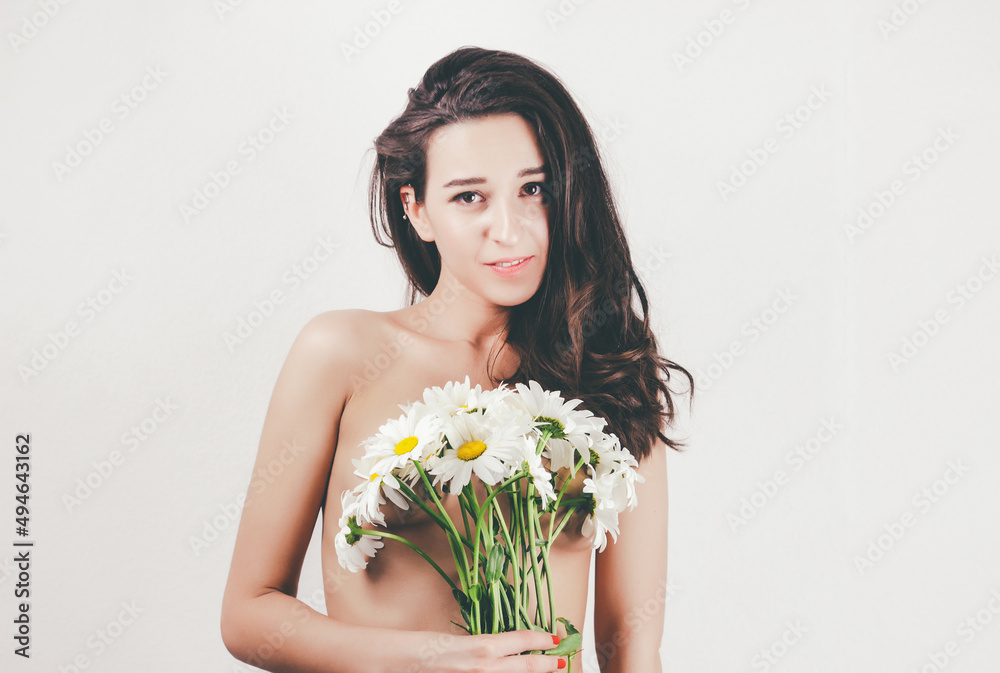 Beautiful woman with clean fresh skin holding flowers. Nude girl with daisies. A beautiful figure of a naked female body with a chamomile flower. concept of health and motherhood. light background. Beautiful woman with clean fresh skin holding flowers. Nude girl with daisies. A beautiful figure of a naked female body with a chamomile flower. concept of health and motherhood. light background.