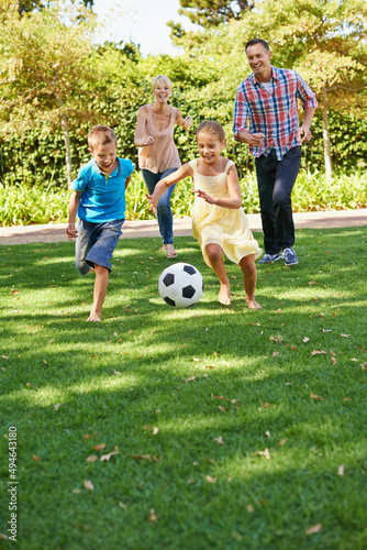 Family fun at the park. A happy family playing soccer in the park on a beautiful summer day.