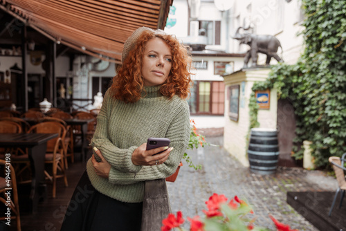 Photography A woman in a beret and a green sweater holds a phone in her hands and takes shoo
