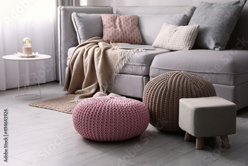 Stylish poufs and ottoman near sofa in living room. Interior element photo