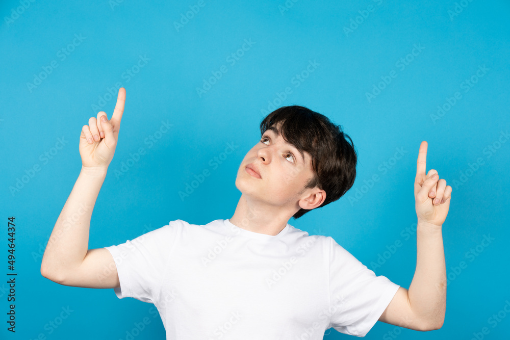 Handsome teenager boy pointing up on blue background. Handsome teenager boy pointing up on blue background.