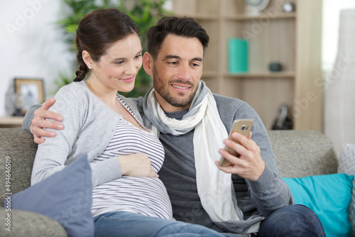 Fotografie expectant couple on sofa looking at smartphone