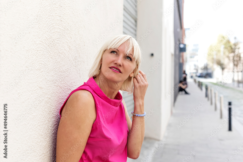 Fototapeta premium Pretty young city girl standing against an exterior wall