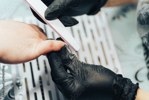 Manicurist processes nails with file.