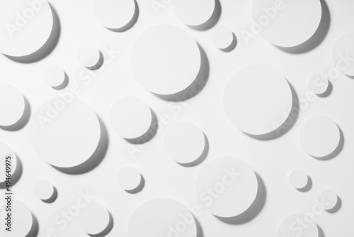 White paper circles different size as abstract random pattern in hard light with grey strict shadows  top view. Contemporary simple stable abstract background.