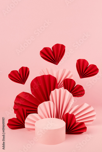 Valentines day soft pastel pink stage mockup for presentation cosmetic product, advertising, design with one round podium, fly red and pink hearts of paper fans in asian style, copy space, vertical.