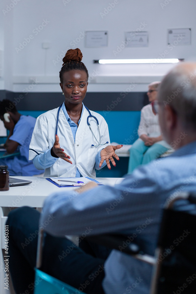 Clinic practitioner specialist discussing with retired man in wheelchair about effects of prescribed antiviral. Doctor explaining medication benefits and recovery results to elder person Clinic practitioner specialist discussing with retired man in wheelchair about effects of prescribed antiviral. Doctor explaining medication benefits and recovery results to elder person