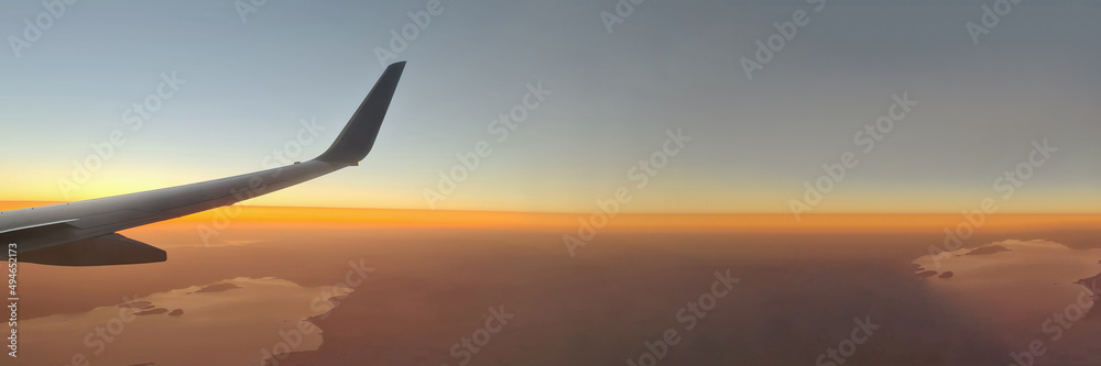 Obraz premium Closeup of airplane wing above ground at sunset background