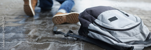 Tableau sur toile Backpack lying on slippery paving slabs near falling man closeup