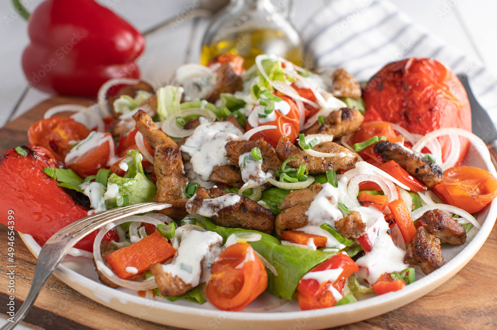 Low carb salad with meat, roasted vegetables, lettuce and yogurt dressing