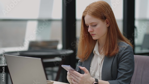 woman is working with laptop remotely in cafe, sending message by smartphone and checking notice in mobile phone
