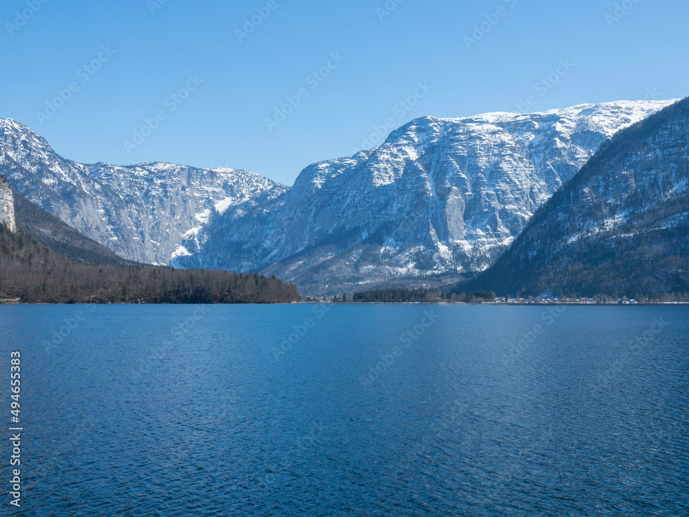 Panoramic view of the crystal-clear Lake Hallstatt. In the background the Dachstein glacier with a cloudless blue sky. Hallstatt, Salzkammergut, Upper Austria. Place for text.