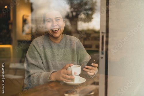 Obraz na płótnie Chica joven guapa tomando té en una cafetería muy acogedora con sudadera gris y mirando el smartphone w salonie