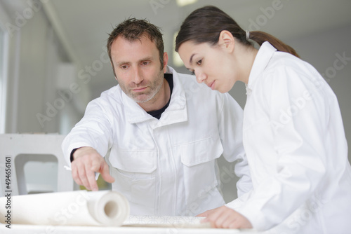 house painter and apprentice paint a wall