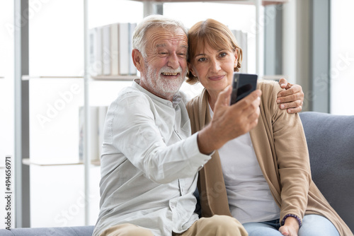 senior couple video call to someone or selfie from smartphone on sofa
