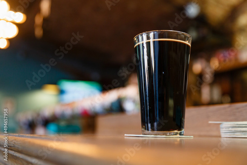 A mug of dark beer on a wooden bar  close-up  with a blurred background.