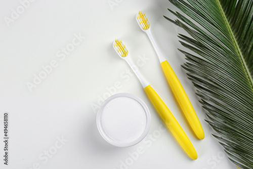 Toothbrushes and bowl of baking soda on beige background  flat lay. Space for text