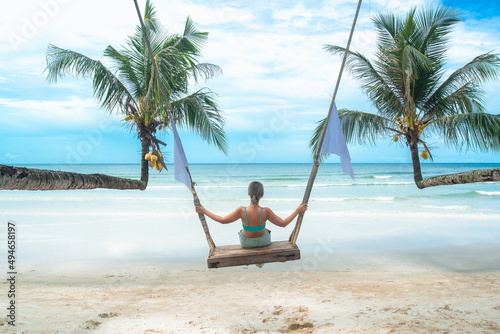 Young beauty lady sitting on rope swings on the beach, travel and relax concept.