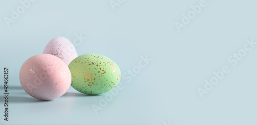 Three decorative pastel eggs on blue background. Happy Easter greeting card with copy space. Banner. Invitation.