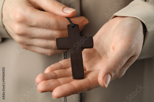 Woman holding wooden Christian cross, closeup view