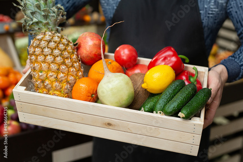 Ecoproduct. A set of fresh vegetables and fruits in a box, which the man holds in his hands. The man in the apron. Vegetable Set photo