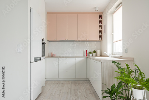 Kuchnia w minimalistycznym nowoczesnym stylu. Białe i różowe fronty mebli oraz sprzęt. Biała lodówka