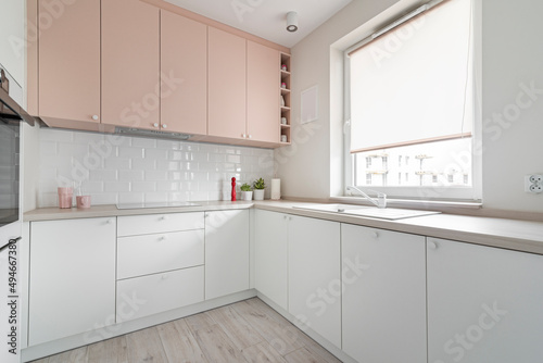Fototapeta Naklejka Na Ścianę i Meble -  Kuchnia w minimalistycznym nowoczesnym stylu. Białe i różowe fronty mebli oraz sprzęt.