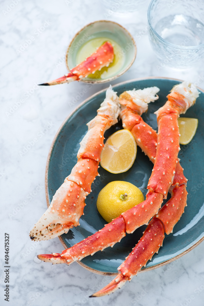 Turquoise plate with boiled legs and claws of kamchatka crab, vertical shot on a light-grey marble background, middle closeup Turquoise plate with boiled legs and claws of kamchatka crab, vertical shot on a light-grey marble background, middle closeup
