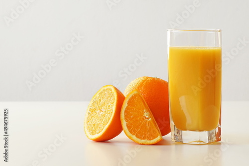 A glass of freshly squeezed orange juice, fresh and juicy orange, A boost of energy, vivacity and vitamin C. Objects are located on the side - there is free space