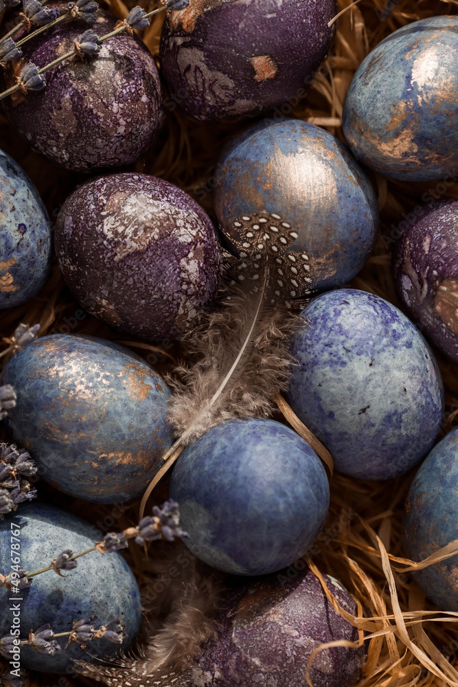 Obraz premium Purple, blue and golden eggs on a dark concrete background. The purple hue trend of 2022 is very peri. Easter card with a copy of the place for the text. Natural dye karkade tea. Top view.