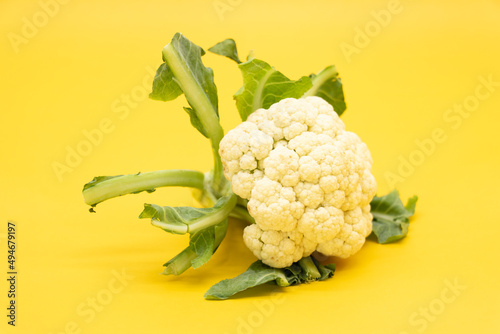 Cauliflower with leaves isolated on yellow background, photo