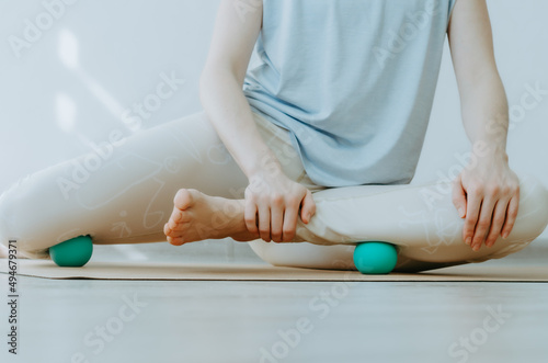 Person doing yin yoga and myofascial release on outer shin muscles and inner knee adductors. Concept: self-care practices at home, SMFR, myoyin	 photo