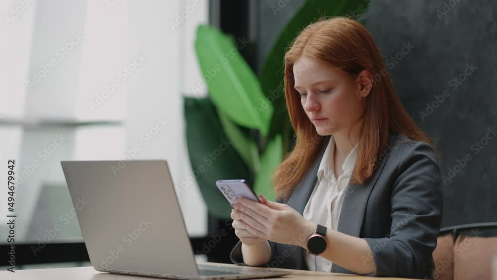 pretty redhead woman is working in office of big modern company, using private smartphone on workplace pretty redhead woman is working in office of big modern company, using private smartphone on workplace