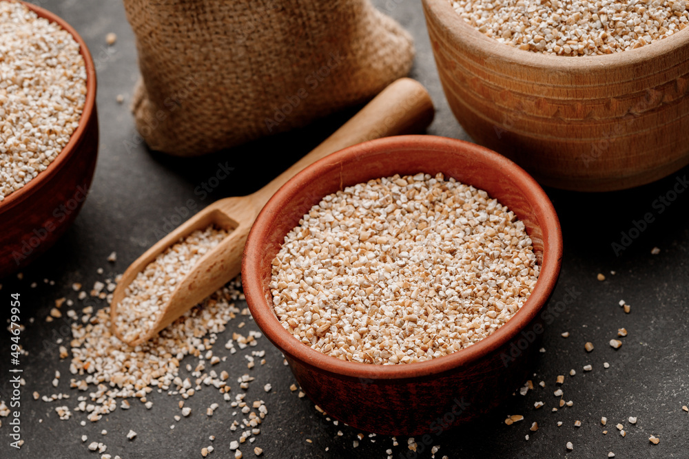 Barley groats in bowls and bags on a dark background. High quality photo Barley groats in bowls and bags on a dark background. High quality photo