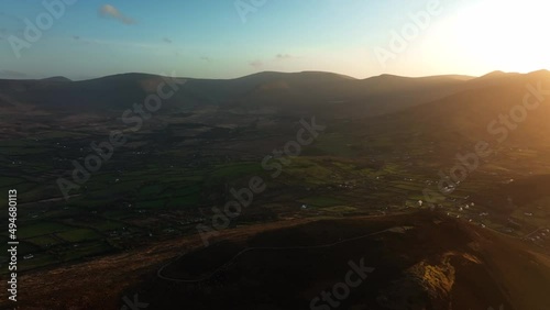 Glenbeigh, Kerry, Ireland, March 2022. Drone slowly pushes west along the Iveragh Peninsula high above the houses and fields during a golden sunset. photo