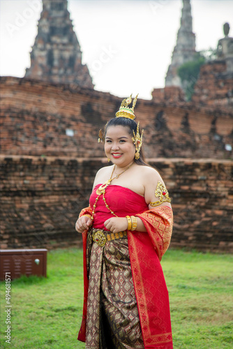 Portrait smiling Asian woman in a Thai dress with an old pagoda background © tisomboon