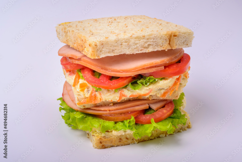 Big sandwich with smoked ham, cream, lettuce and tomato isolated on white background. Fast food. Big sandwich with smoked ham, cream, lettuce and tomato isolated on white background. Fast food.