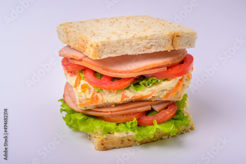 Big sandwich with smoked ham, cream, lettuce and tomato isolated on white background. Fast food.