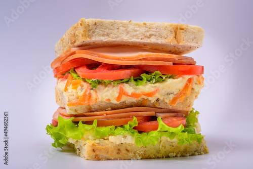 Big sandwich with smoked ham, cream, lettuce and tomato isolated on white background. Fast food.