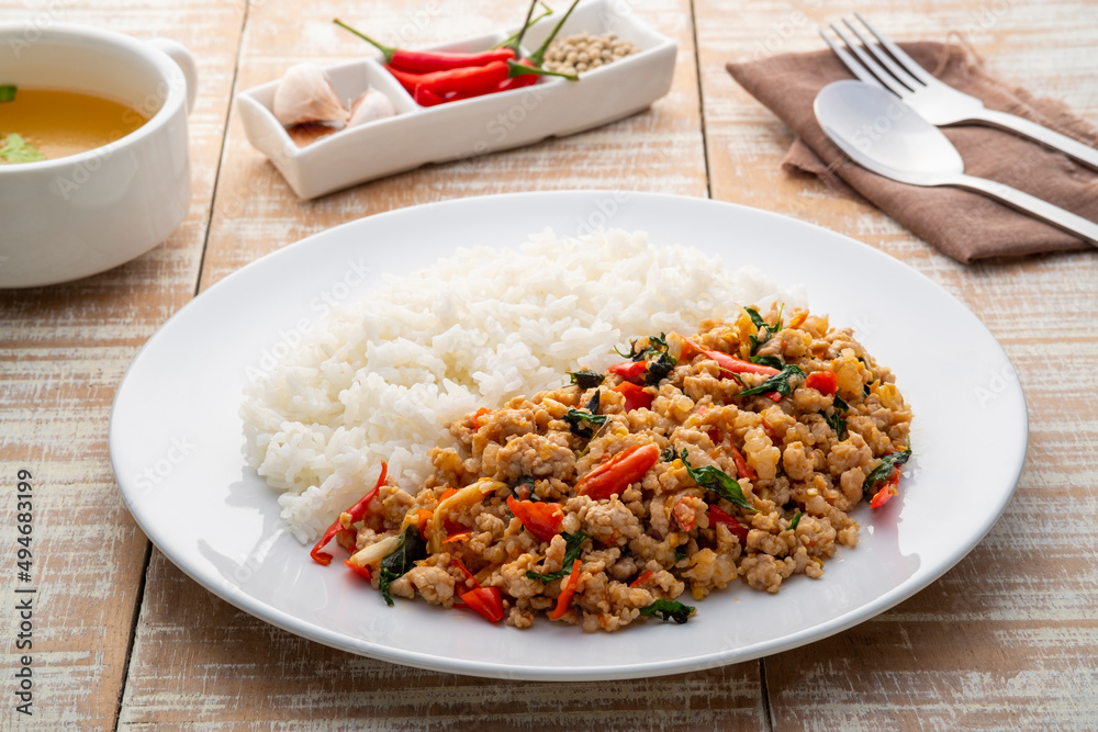 Stir fried pork and basil,fry minced pork and basil with oyster sauce in white plate with cooked thai jasmine rice,famous food in Thailand(khao kaprao moosub)