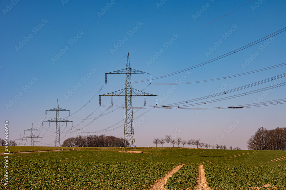 custom made wallpaper toronto digitalBeautiful farm landscape and high voltage power lines in Germany, at Spring during sunset with blue sky. Concept of energy supply and energy crisis.
