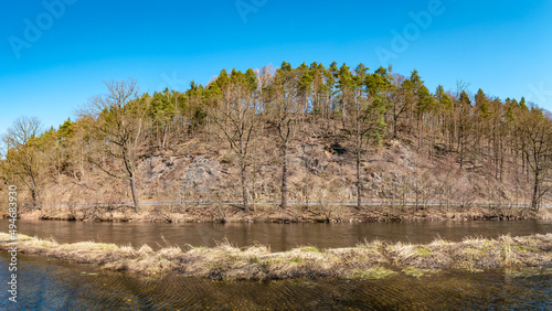 Panoramic view over magical deciduous forest, rocky granite hills landscape at riverside of Zschopau river near Mittweida town, Saxony, Germany, at warm sunset and blue Spring sky.