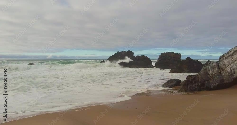 Foamy waves breaking over cliffy shoreline. Blue turquoise wave water texture. cinematic shot over wavy stormy beach. Evening, twilight. Beautiful sea, destination Europe, Portugal. Sintra Foamy waves breaking over cliffy shoreline. Blue turquoise wave water texture. cinematic shot over wavy stormy beach. Evening, twilight. Beautiful sea, destination Europe, Portugal. Sintra
