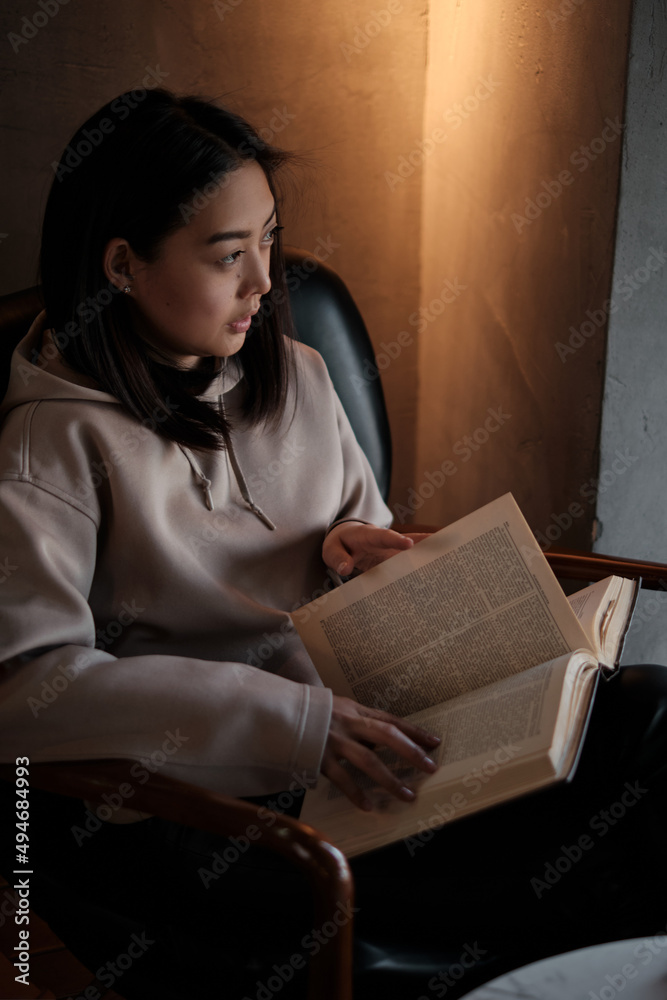 Naklejka premium Shot of young asian female student sitting at table and writing on notebook. Young female student studying in cafe.