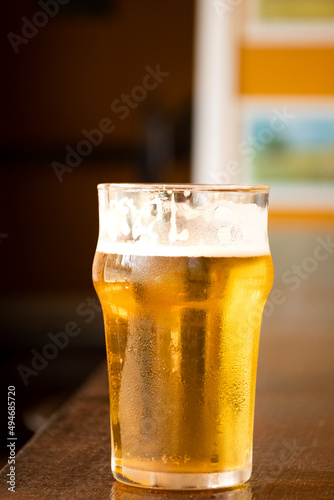 Obraz na plátně close up half pint of pale lager pilsen beer with blurred background on pub coun