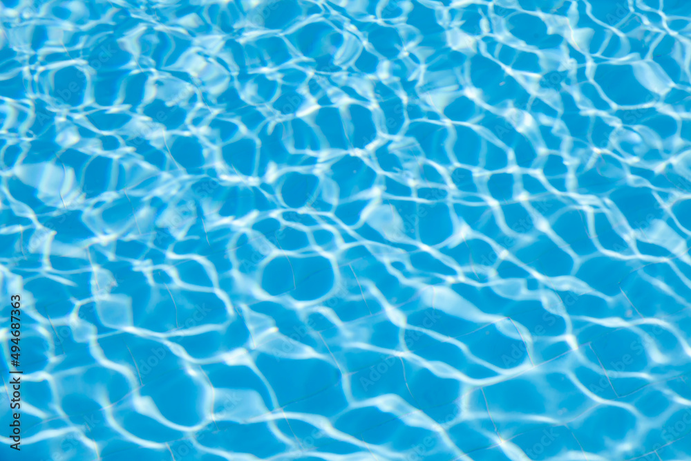 Blurred transparent ripple of blue clear water texture in a swimming pool in sunlight.