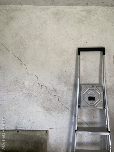 a stepladder leaning against a white wall that has a crack in it 