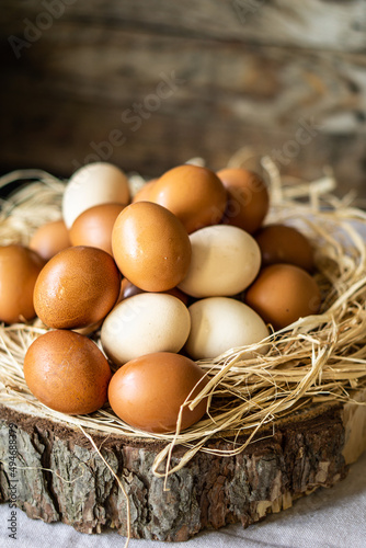 Front view of fresh raw eggs on hay and wood over wooden brown rustic background